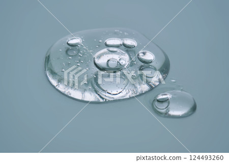 Textured round drop of serum with bubbles on dark green background. Textured round drop of serum with bubbles on dark green background. 124493260