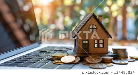 a real estate company, a small figure of a house, a laptop and coins, the concept of online buying and selling housing, expensive real estate value 124493824