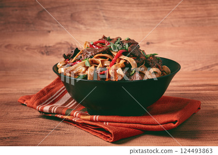 Udon noodles with beef in Mongolian style, with green onions and vegetables, homemade, on a wooden table, 124493863