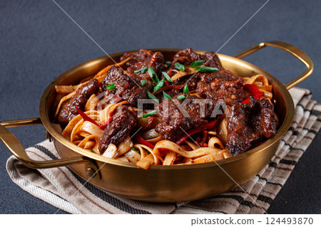 Udon noodles with beef in Mongolian style, with green onions and vegetables, homemade, on a dark background, Udon noodles with beef in Mongolian style, with green onions and vegetables, homemade, on a dark background, 124493870