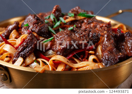 Udon noodles with beef in Mongolian style, with green onions and vegetables, homemade, on a dark background, Udon noodles with beef in Mongolian style, with green onions and vegetables, homemade, on a dark background, 124493871