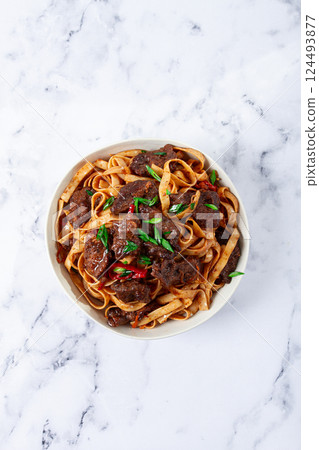 Udon noodles with Mongolian beef, green onions and vegetables, in a white plate, on a light background, homemade, no people, 124493877