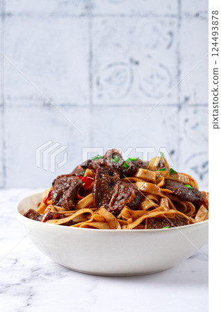 Udon noodles with Mongolian beef, green onions and vegetables, in a white plate, on a light background, homemade, no people, 124493878