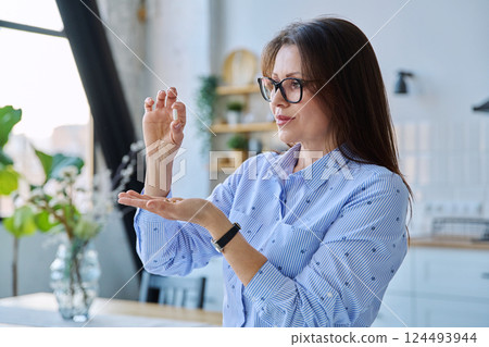 Middle aged smiling woman holding vitamins, supplements, capsules Middle aged smiling woman holding vitamins, supplements, capsules 124493944