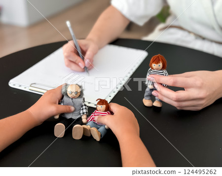 Child therapy session with caucasian female therapist using dolls for emotional expression Child therapy session with caucasian female therapist using dolls for emotional expression 124495262