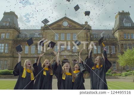 Students throw their graduation hats in the air to celebrate graduation, confetti flying in the air 124495516