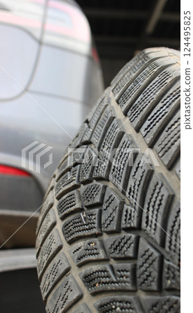 Macro photo of a tire removed from a car against the background of blurred taillights on the car bumper Macro photo of a tire removed from a car against the background of blurred taillights on the car bumper 124495825