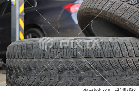 Old worn tires stacked near car trunk after tire change at auto workshop 124495826
