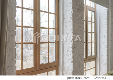 Large windows with wooden frames in loft interior with white brick walls inside apartment or house Large windows with wooden frames in loft interior with white brick walls inside apartment or house 124496129