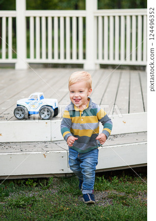 Happy Toddler Playing with Toy Truck on Wooden Porch 124496352