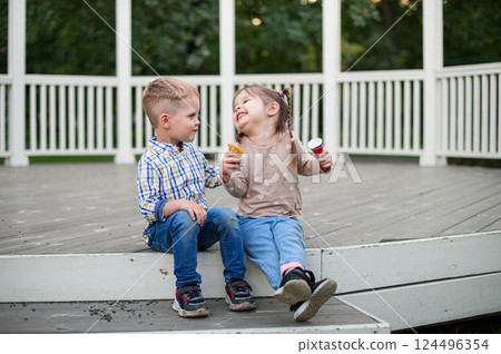 Happy Children Eating Ice Cream Outdoors on a Wooden Terrace Happy Children Eating Ice Cream Outdoors on a Wooden Terrace 124496354