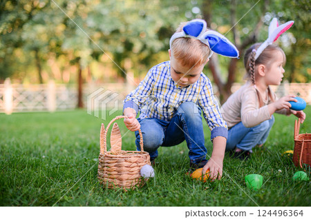 Children Hunting Easter Eggs in the Garden with Bunny Ears 124496364