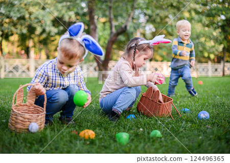 Children Hunting Easter Eggs in the Garden with Bunny Ears Children Hunting Easter Eggs in the Garden with Bunny Ears 124496365