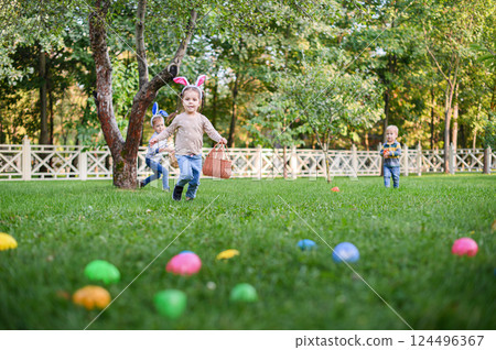 Children Hunting Easter Eggs in the Garden with Bunny Ears Children Hunting Easter Eggs in the Garden with Bunny Ears 124496367