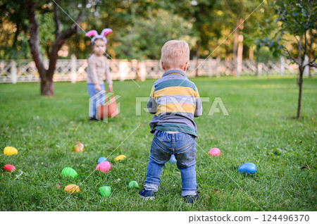 Children Hunting Easter Eggs in the Garden with Bunny Ears Children Hunting Easter Eggs in the Garden with Bunny Ears 124496370