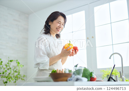 A middle-aged woman cooking while looking at a recipe on a tablet A middle-aged woman cooking while looking at a recipe on a tablet 124496713