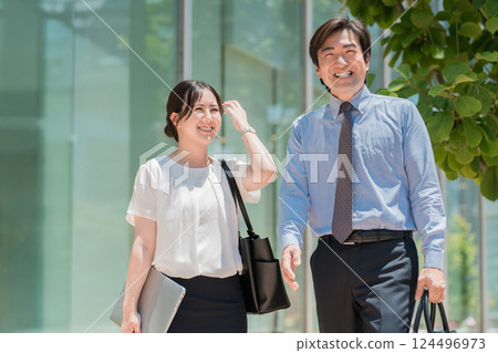 穿著西裝的商人和女士走過辦公區 穿著西裝的商人和女士走過辦公區 124496973