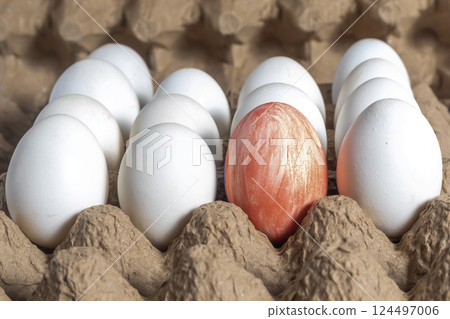Red egg stands out among white eggs on a cardboard tray. Happy Easter Red egg stands out among white eggs on a cardboard tray. Happy Easter 124497006