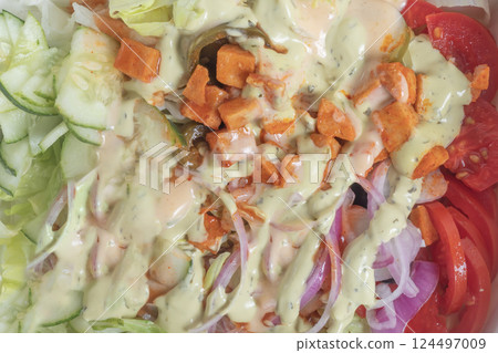 Close-up of fresh vegetable salad with creamy dressing and crunchy toppings. Close-up of fresh vegetable salad with creamy dressing and crunchy toppings. 124497009