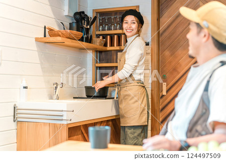 A husband talking to his wife who is cooking in a mini kitchen during a family trip to a cottage 124497509