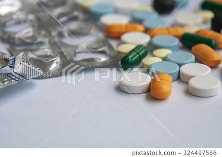 Variety of colorful pills and capsules scattered on a light colored surface with customizable space for text. Variety of colorful pills and capsules scattered on a light colored surface with customizable space for text. 124497536