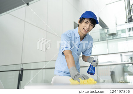 Smiling young male cleaning staff looking at camera 124497896