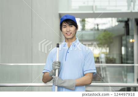 Smiling young male cleaning staff looking at camera 124497918
