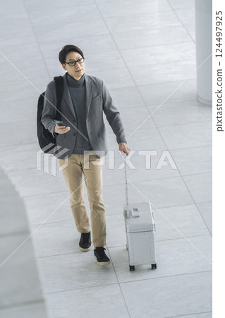 A man in his 40s walking with a carry bag and a smartphone 124497925