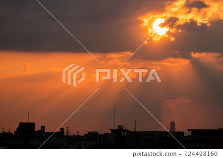 A dramatic sunset with light shining through the clouds and a city silhouette A dramatic sunset with light shining through the clouds and a city silhouette 124498160