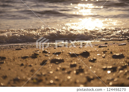 At the beach lit by the setting sun 124498270