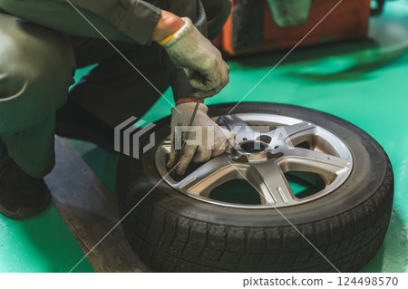 Hands of an auto mechanic measuring tire pressure and inflating tires Hands of an auto mechanic measuring tire pressure and inflating tires 124498570