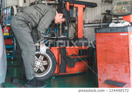 A male mechanic/service technician changing tires using a tire changer A male mechanic/service technician changing tires using a tire changer 124498572