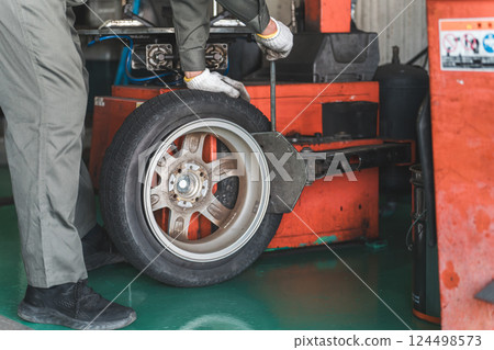 A male mechanic/service technician changing tires using a tire changer 124498573