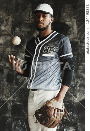 Baseball, sports and uniform with a man athlete on a dark background wearing a mitt while holding a ball. Portrait, sport and confident with a male baseball player standing against a dugout wall 124498828