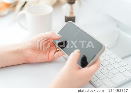 一位留著指甲的女人正在看著智慧型手機的橫向螢幕 124498857