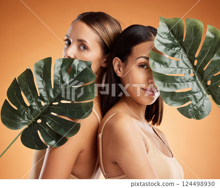 Diversity, beauty and skincare women friends with a plant leaf. Portrait of young cosmetic models with organic detox treatment, healthy and skin wellness against an orange mockup space background Diversity, beauty and skincare women friends with a plant leaf. Portrait of young cosmetic models with organic detox treatment, healthy and skin wellness against an orange mockup space background 124498930