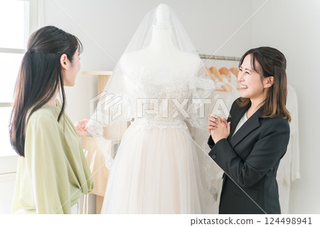 A woman having a meeting with a wedding planner and dress coordinator to choose a dress A woman having a meeting with a wedding planner and dress coordinator to choose a dress 124498941