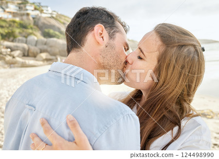 Happy, kiss and couple on a beach with love from engagement announcement or anniversary. Happiness, relax and care of a woman and man together by the sea and ocean outdoor with commitment Happy, kiss and couple on a beach with love from engagement announcement or anniversary. Happiness, relax and care of a woman and man together by the sea and ocean outdoor with commitment 124498990