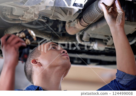 Car, mechanic in garage and service inspection of motor vehicle for maintenance or safety. Auto shop, automobile workshop engineer and repairman working with torch to check vehicle pipe for oil leak 124499008