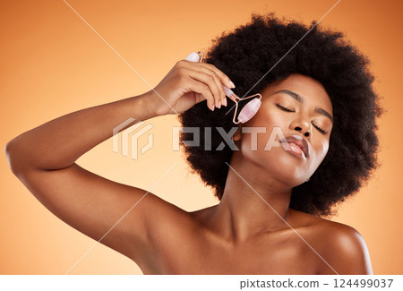 Facial beauty, black woman or roller wellness, aesthetic or health makeup, glowing skincare or clean cosmetics on orange studio background. Smile young girl face model, afro or firm skin care 124499037