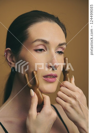 Beauty ritual using wooden tools for facial contouring in a studio 124499085