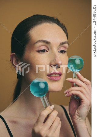 Model demonstrating skincare routine with cool blue face tools Model demonstrating skincare routine with cool blue face tools 124499105