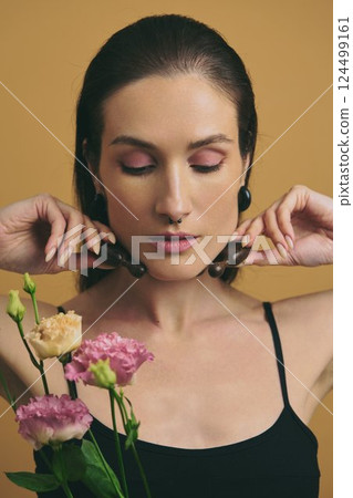 Woman with flowers posing gracefully against a yellow background Woman with flowers posing gracefully against a yellow background 124499161