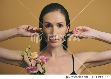Woman holding flowers and chocolate against warm background in indoor setting Woman holding flowers and chocolate against warm background in indoor setting 124499163