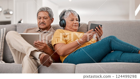 Senior couple, relax with technology and tablet, smartphone and headphones, streaming and watching online with 5g network. Elderly, man and woman with device, sofa and together in retirement. 124499298