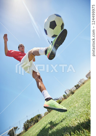 Football, fitness and soccer player training with a juggling exercise on soccer field, grass or football stadium. Sports, jumping and below view of a healthy athlete with skills and creative talent Football, fitness and soccer player training with a juggling exercise on soccer field, grass or football stadium. Sports, jumping and below view of a healthy athlete with skills and creative talent 124499975
