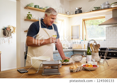 Wine, cooking and senior man in the kitchen preparing a meal for dinner or lunch at his home. Happy, retirement and elderly guy drinking an alcohol beverage with food to cook for a date at his house. 124500133