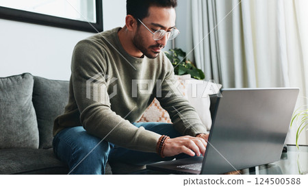 Typing, online and laptop with man on sofa for freelancer, networking and email response. Reading, communication and remote worker with person in living room of home for business proposal or research 124500588
