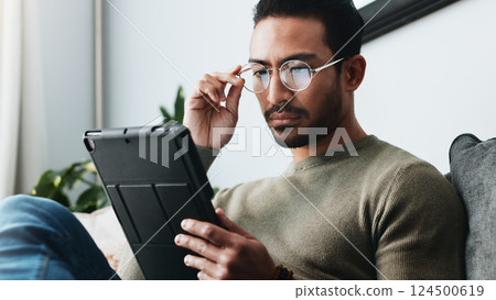 Tablet, glasses and man on sofa in home reading online blog, post or news article for politics. Digital technology, research and male person with social networking in living room at apartment. Tablet, glasses and man on sofa in home reading online blog, post or news article for politics. Digital technology, research and male person with social networking in living room at apartment. 124500619