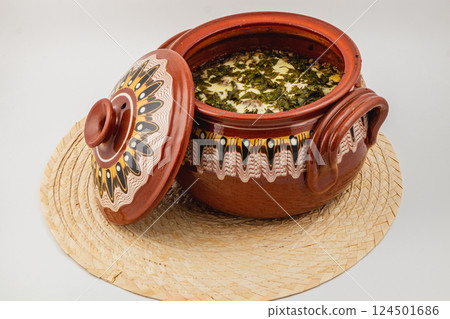 Traditional clay pot filled with vibrant green stew on woven mat Traditional clay pot filled with vibrant green stew on woven mat 124501686